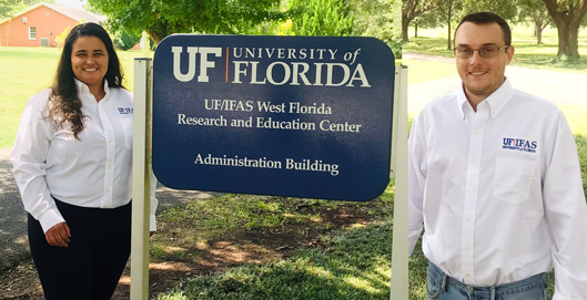Julia and Marcelo stand next to building sign. UF/IFAS Weasr Florida Research and Education Center. Administration Building. 